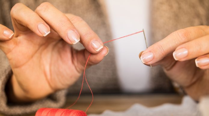 man putting a thread through a needle