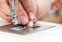 How to Thread a Sewing Machine – Tips and Tricks tailor threading a sewing machine seen from close up